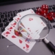 Royal flush poker cards on grey laptop with dice and magnifying glass