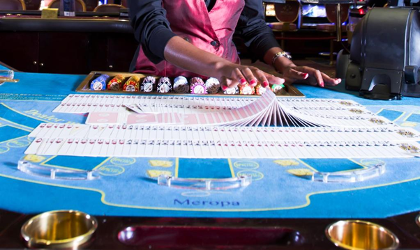 blue casino table with dealer flipping a deck of cards