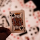 King of spades held by hand, with blurred deck of cards laying face up in the background