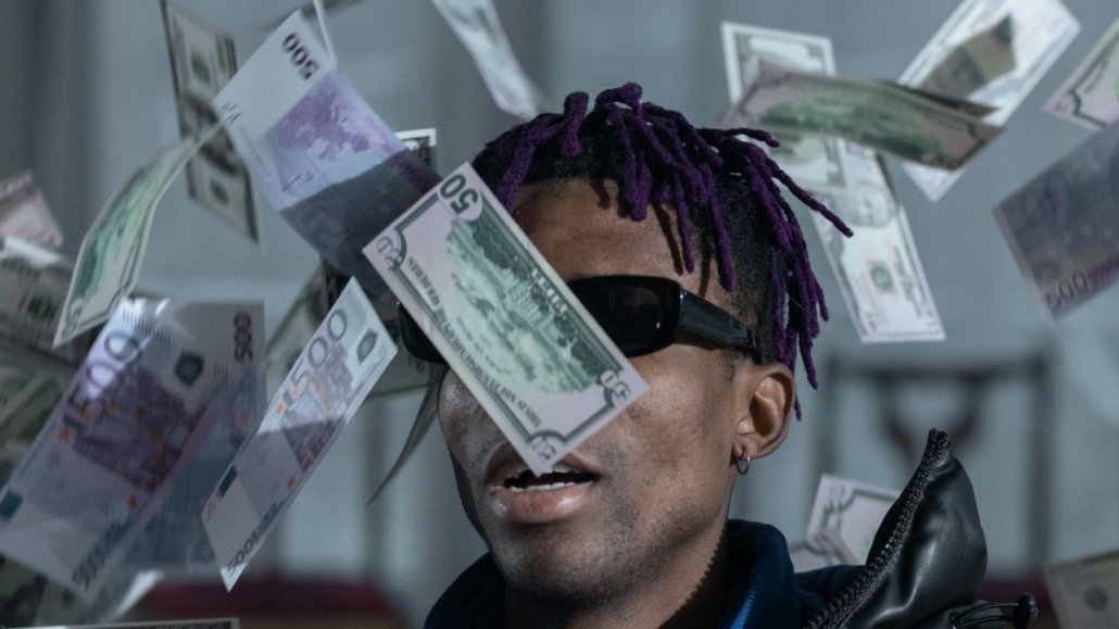 Black man in shades with money falling from the sky